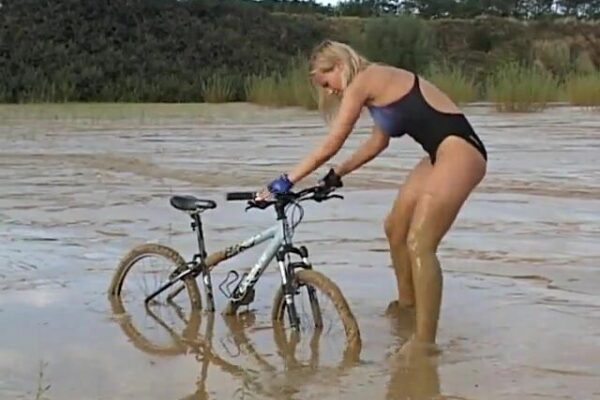 Triathlete girl in swimsuit gets stuck in mud